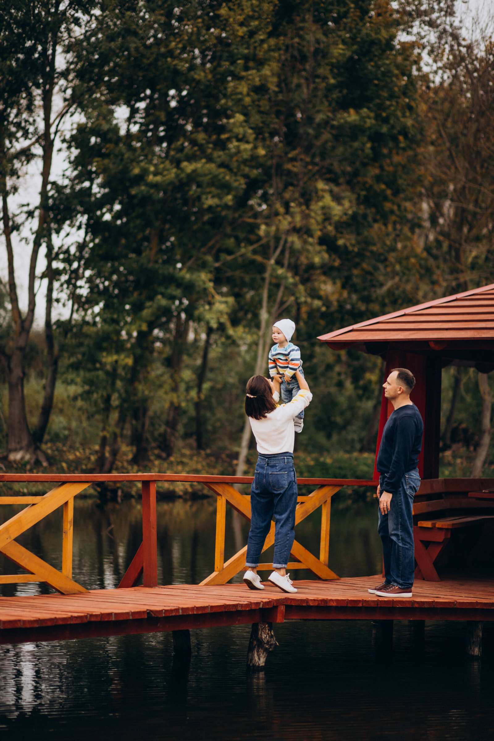 Young family with little son walking on the bridge by the river Young family with little son walking on the bridge by the river